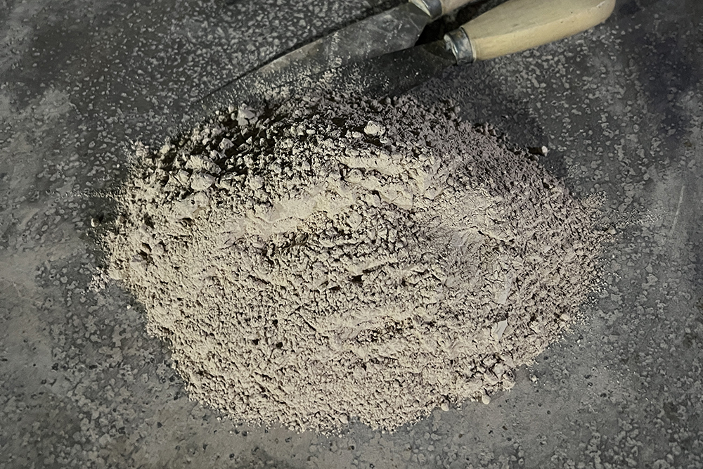 HanBon Forge workshop photograph showing dry clay-based materials and tools used during katana preparation