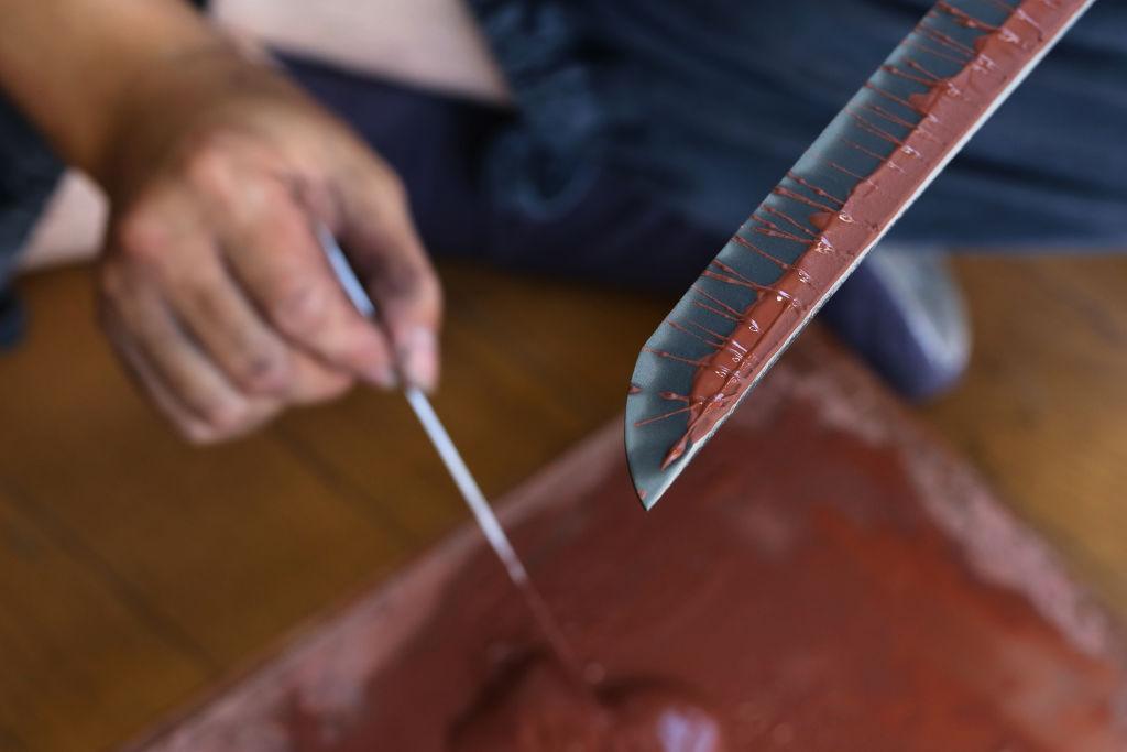 Swordsmith applying clay coating during Japanese katana clay tempering process