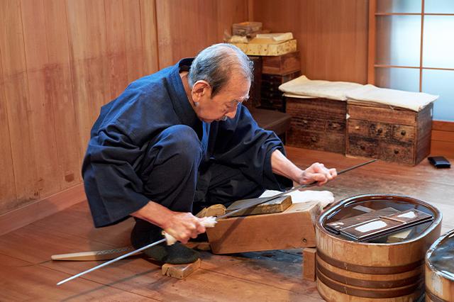 Togishi polishing katana blade with traditional Japanese whetstone Togishi polishing katana blade with traditional Japanese whetstone