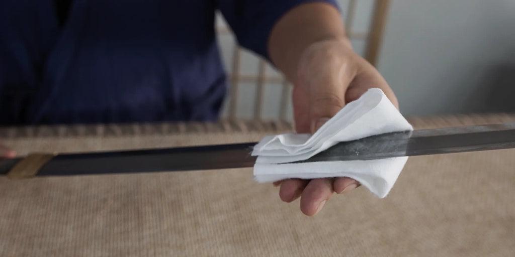 Cleaning a katana blade with a soft cloth before applying new sword oil Cleaning a katana blade with a soft cloth before applying new sword oil