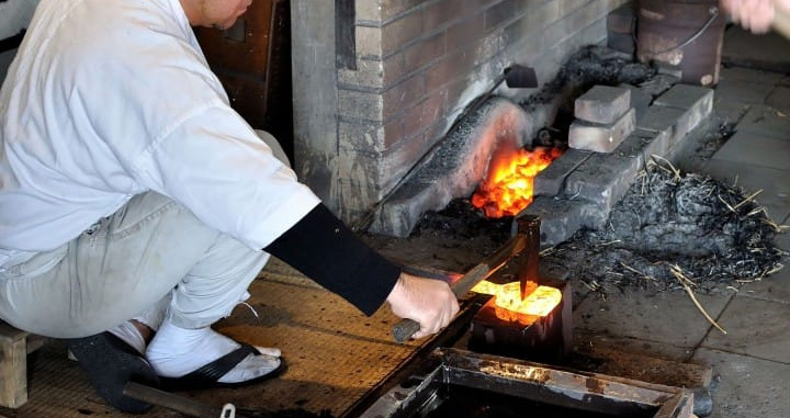 Japanese swordsmith forging folded steel during traditional katana production Japanese swordsmith forging folded steel during traditional katana production