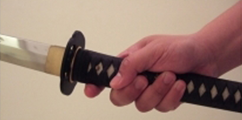 Proper two-handed katana grip showing correct hand placement on the tsuka of a Japanese sword Proper two-handed katana grip showing correct hand placement on the tsuka of a Japanese sword