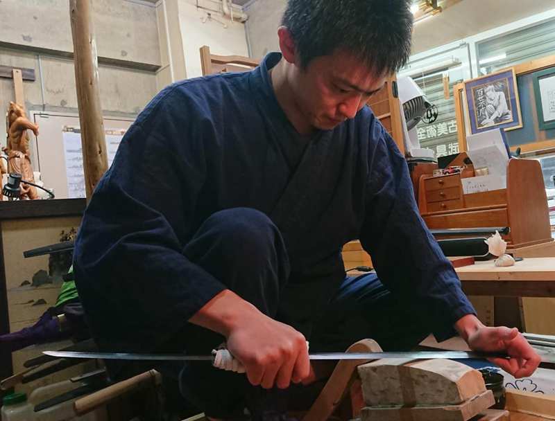 Togishi Japanese sword polisher refining a katana blade with traditional techniques Togishi Japanese sword polisher refining a katana blade with traditional techniques